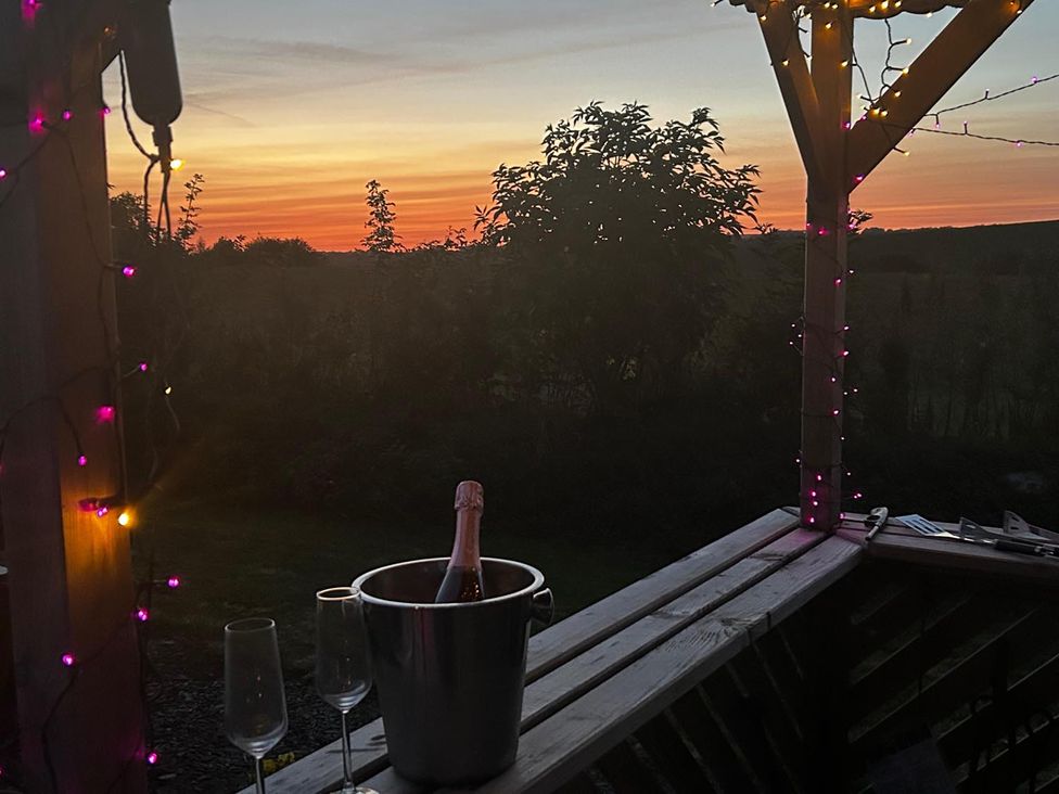 A wooden deck with champagne glasses and a sunset at 