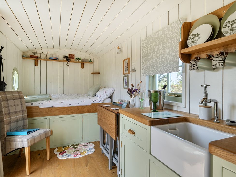 A bedroom with a bed and a kitchen area at Cosy Luxury Owls Roost Hut with Private Hot Tub, Little Deptford Farm near Umberleigh