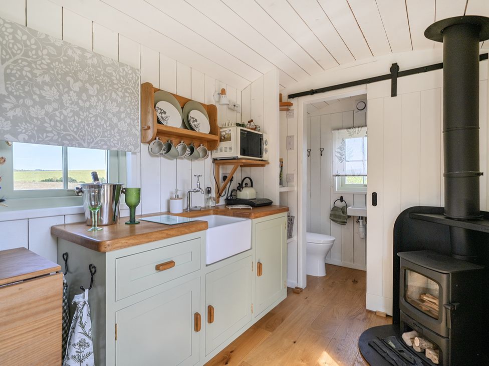 A kitchen with a sink and wood stove at Cosy Luxury Owls Roost Hut with Private Hot Tub Little Deptford Farm near Umberleigh
