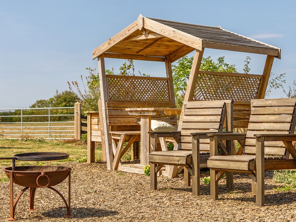 An outdoor seating area with a gazebo, table, and chairs at Cosy Luxury Owls Roost Hut with Private Hot Tub, Little Deptford Farm near Umberleigh