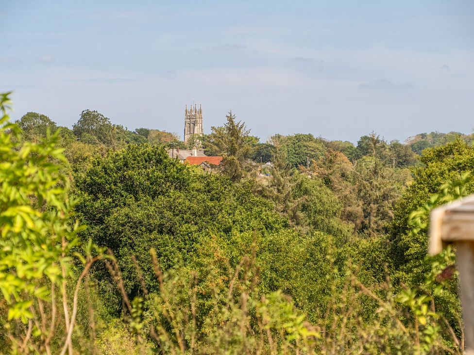 A view of a church tower among trees at Cosy Luxury Owls Roost Hut with Private Hot Tub Little Deptford Farm near Umberleigh