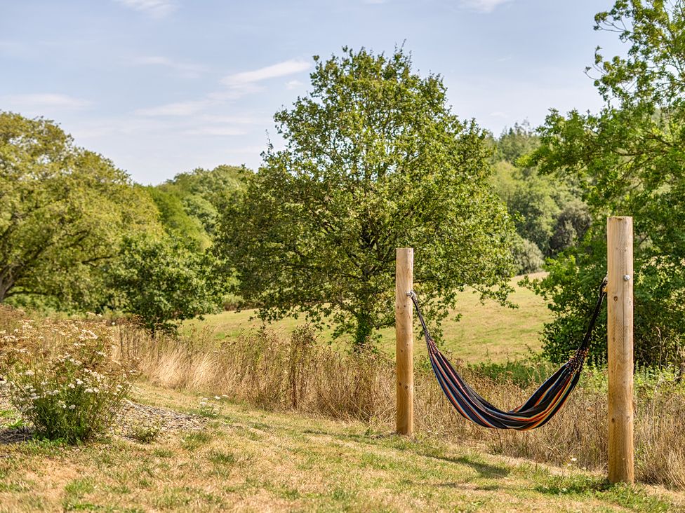 A hammock between wooden posts in a field at Cosy Luxury Owls Roost Hut with Private Hot Tub, Little Deptford Farm near Umberleigh