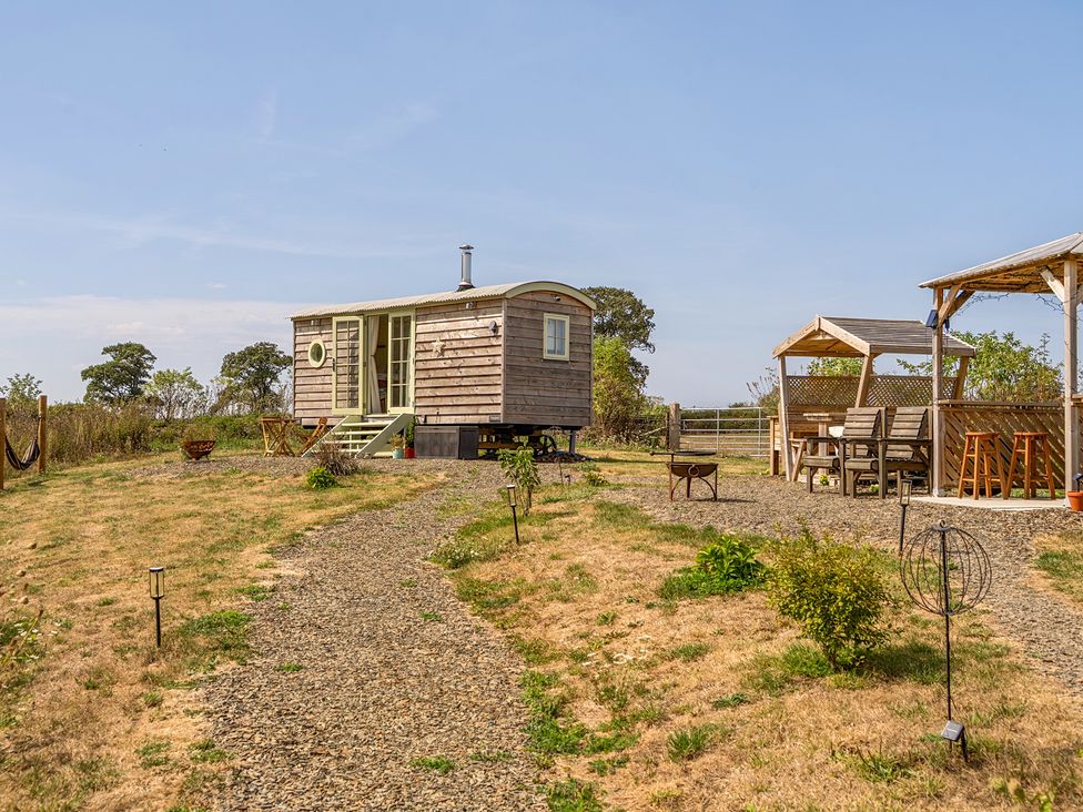 A wooden cabin and outdoor seating area at Cosy Luxury Owls Roost Hut with Private Hot Tub near Little Deptford Farm near Umberleigh