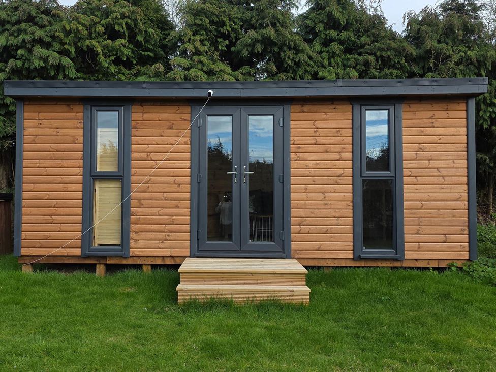 A wooden cabin with double doors and windows at RentMySpaHome with Swimming Pool Hot Tub and Sauna Aughton