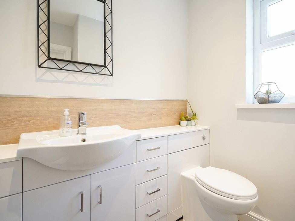 A bathroom with a sink, toilet, mirror, and cabinets at RentMySpaHome with Swimming Pool Hot Tub and Sauna Aughton