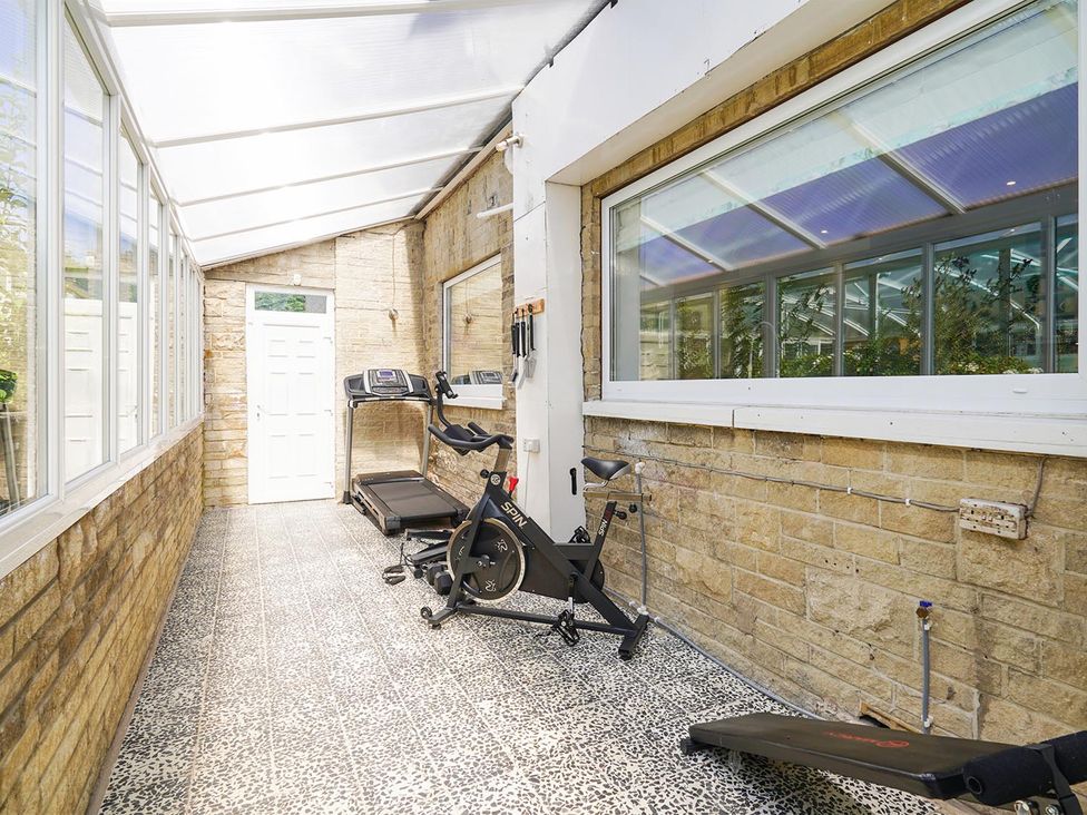 A sunroom with a treadmill and exercise bike at RentMySpaHome with Swimming Pool Hot Tub and Sauna Aughton