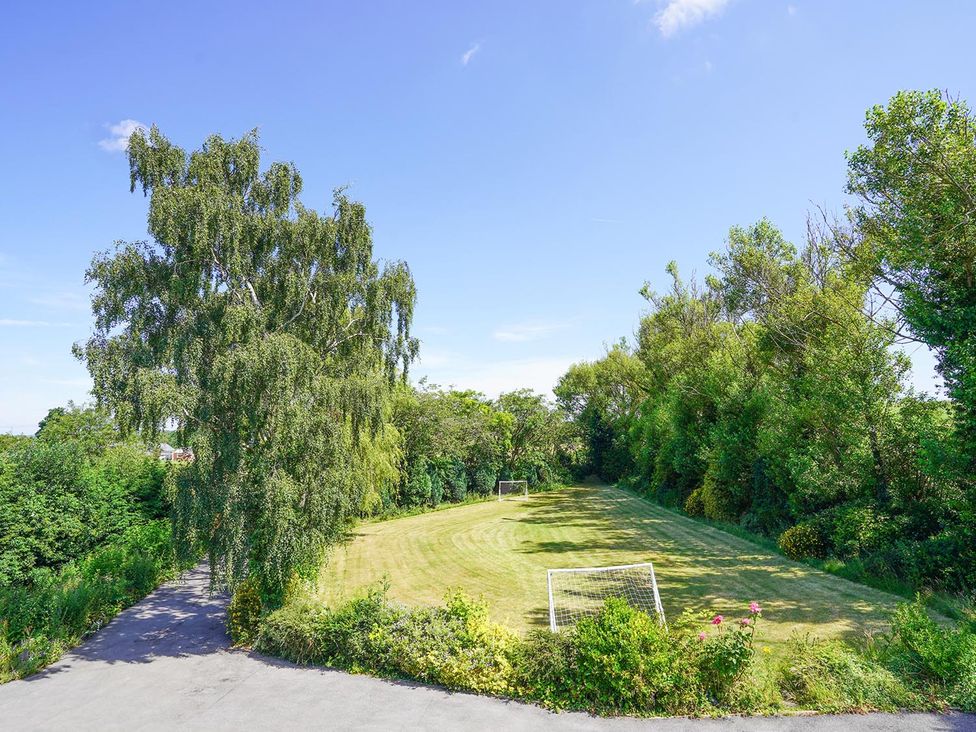 A grassy field with goal posts and trees at RentMySpaHome with Swimming Pool Hot Tub and Sauna in Aughton
