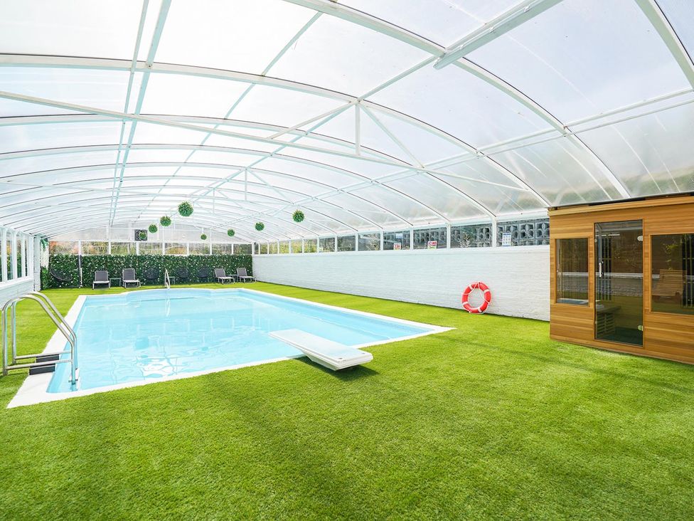 An indoor pool area with a sauna and sun loungers at RentMySpaHome with Swimming Pool Hot Tub and Sauna Aughton