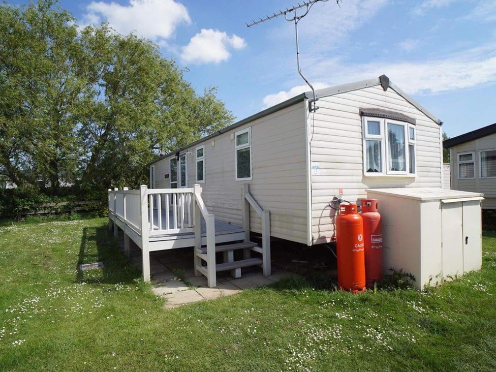 A cabin with a deck and steps in an outdoor area at Cozy 2 bedroom Coastal Chalet in Heacham