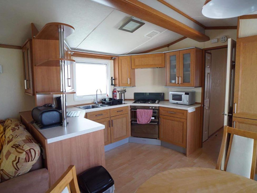 A kitchen with appliances and dining table in Cozy 2 bedroom Coastal Chalet in Heacham