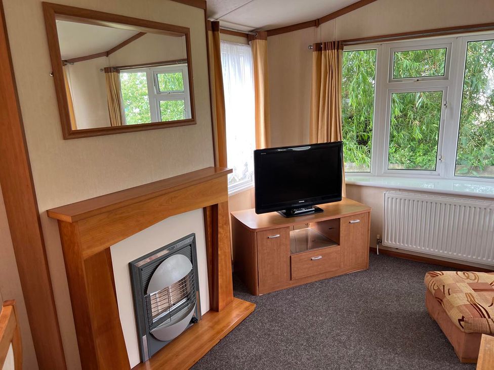 A living room with a television and a fireplace at Cozy 2 bedroom Coastal Chalet in Heacham