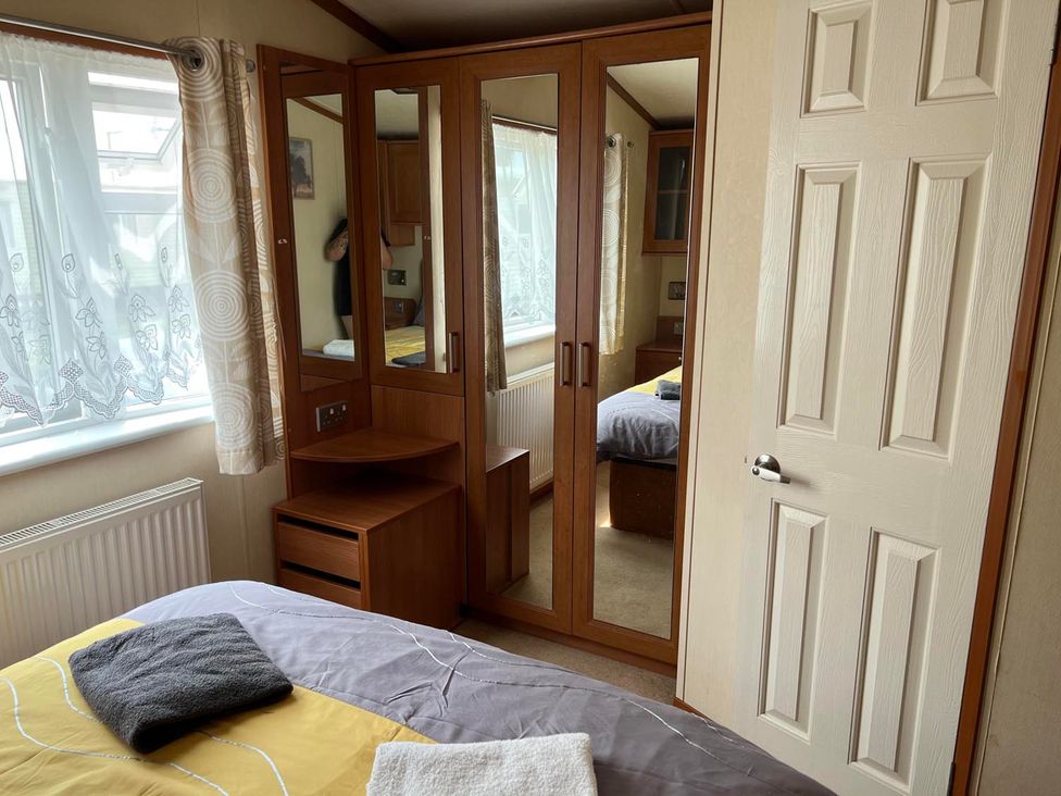 A bedroom with a bed and a mirrored wardrobe at Cozy 2 bedroom Coastal Chalet in Heacham