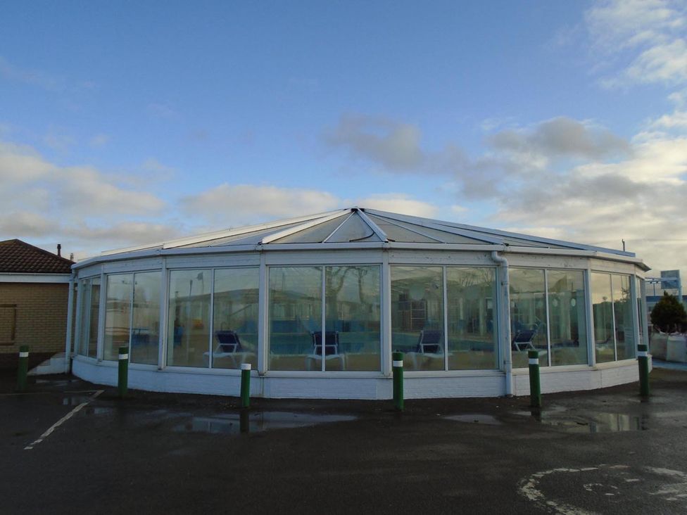 A conservatory with glass walls and blue chairs at Cozy  2 bedroom Coastal Chalet in Heacham