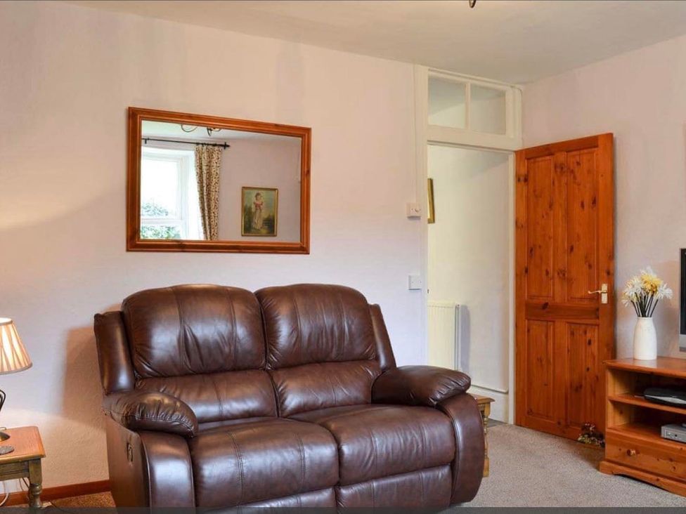 A living room with a sofa and a television stand at The Old Barn in Manchester