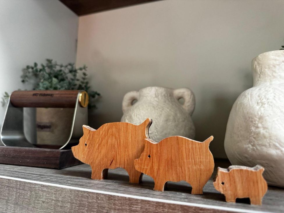 Three wooden pig figures and ceramic vases in a kitchen