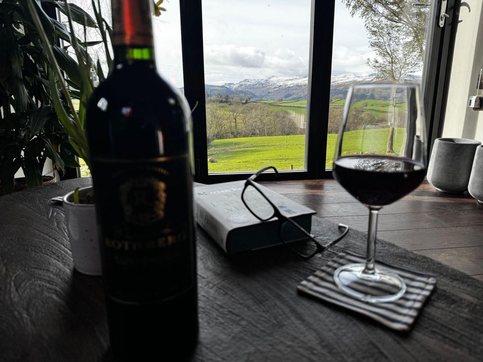 A wine bottle and glass on a table with a view at The Old Barn in Manchester
