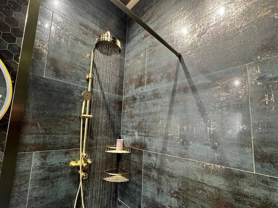 A shower setup with a showerhead and soap dispenser in a bathroom