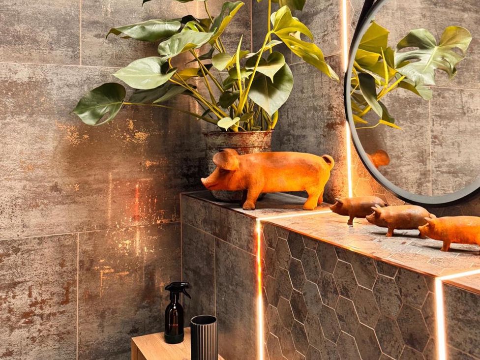 A bathroom with a potted plant and pig statues on a counter