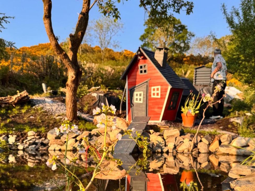 A garden with a small house and pond at The Old Barn in Manchester