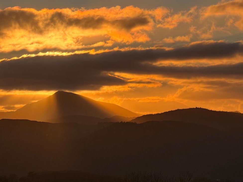 A mountain silhouette against a sunset with clouds in the sky