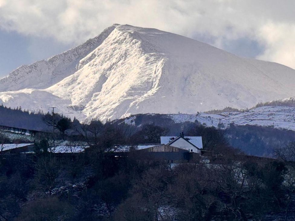 A mountain with snow and a house in the foreground