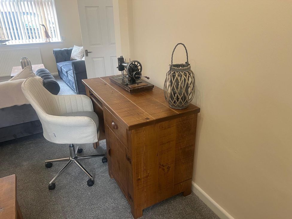 A desk with a sewing machine and chair in a living room