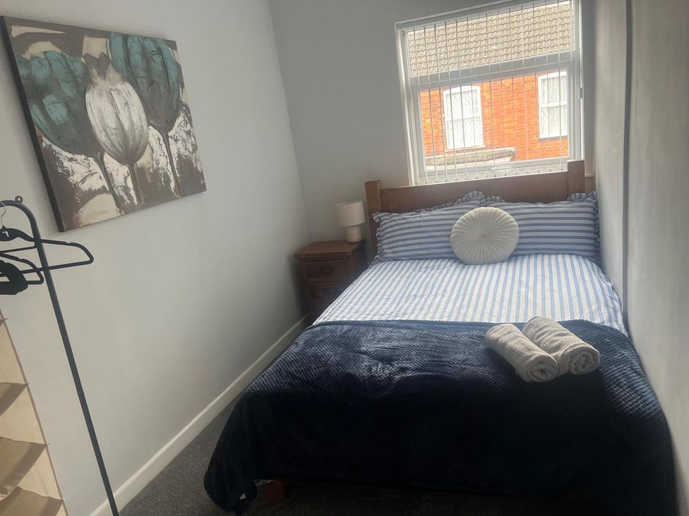 A bedroom with a bed, nightstand, and window at the property