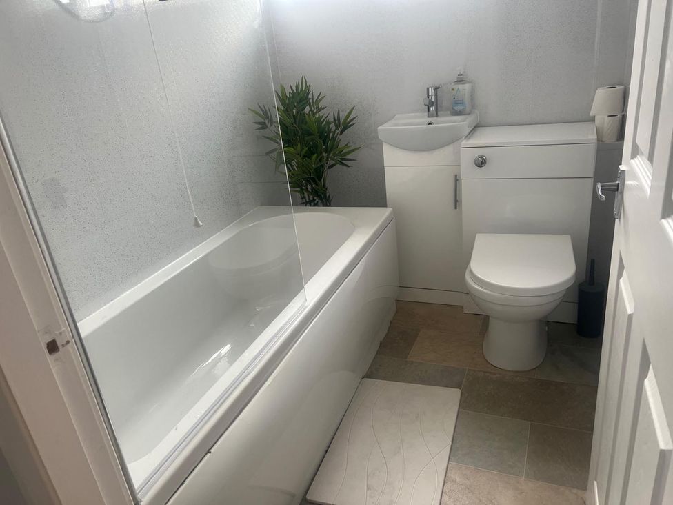 A bathroom with a bathtub, toilet, and sink at The Old Barn in Manchester