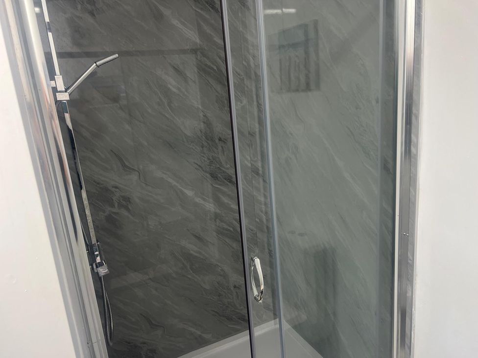 A shower with glass doors and a shower head in a bathroom
