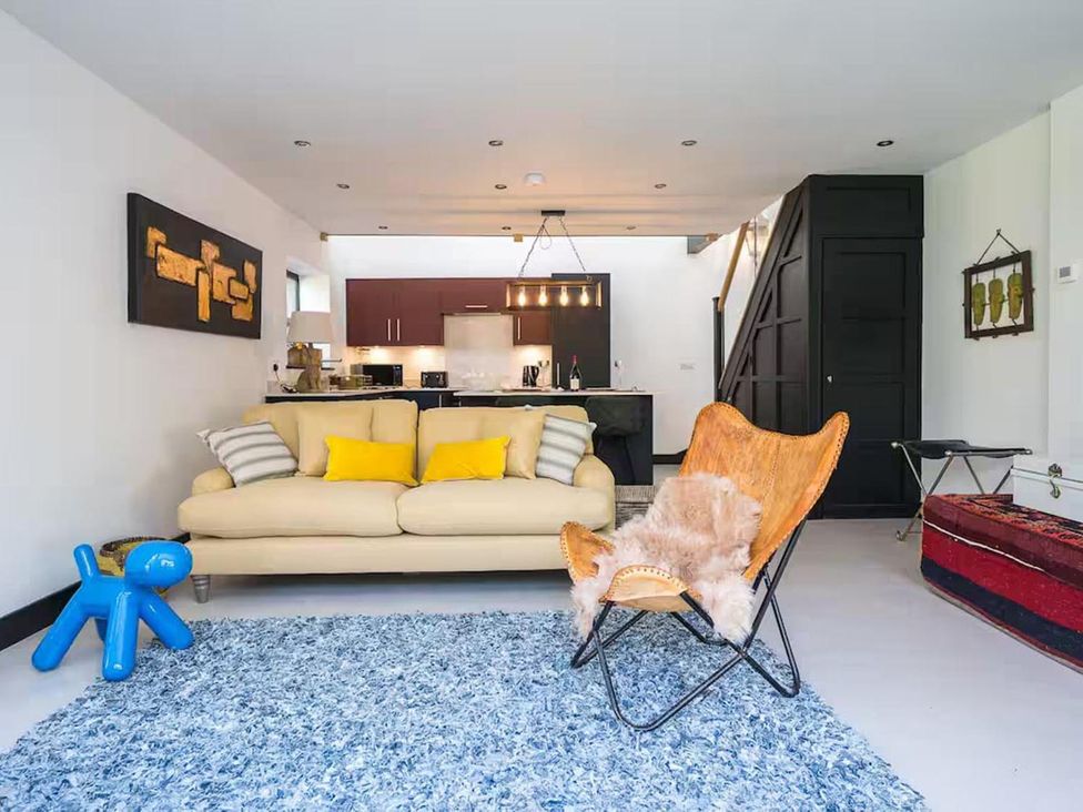 A living room with a sofa and kitchen area at The Old Barn in Manchester