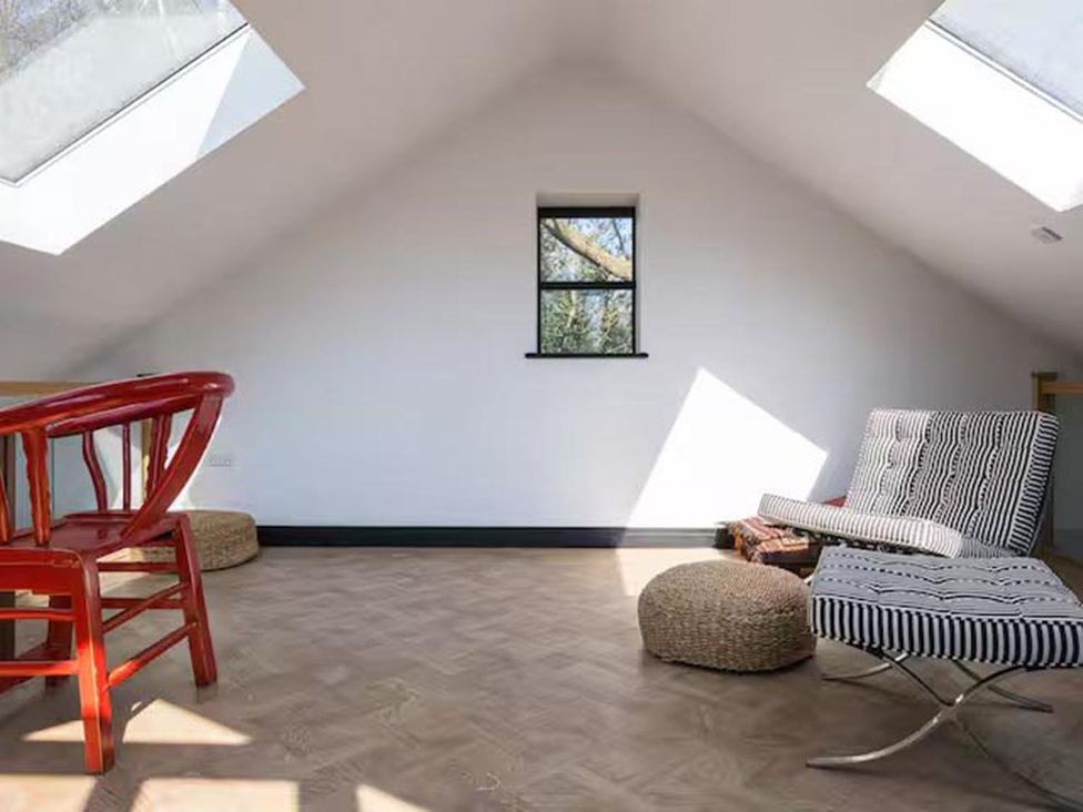 A loft with a red chair, a striped chair, and an ottoman