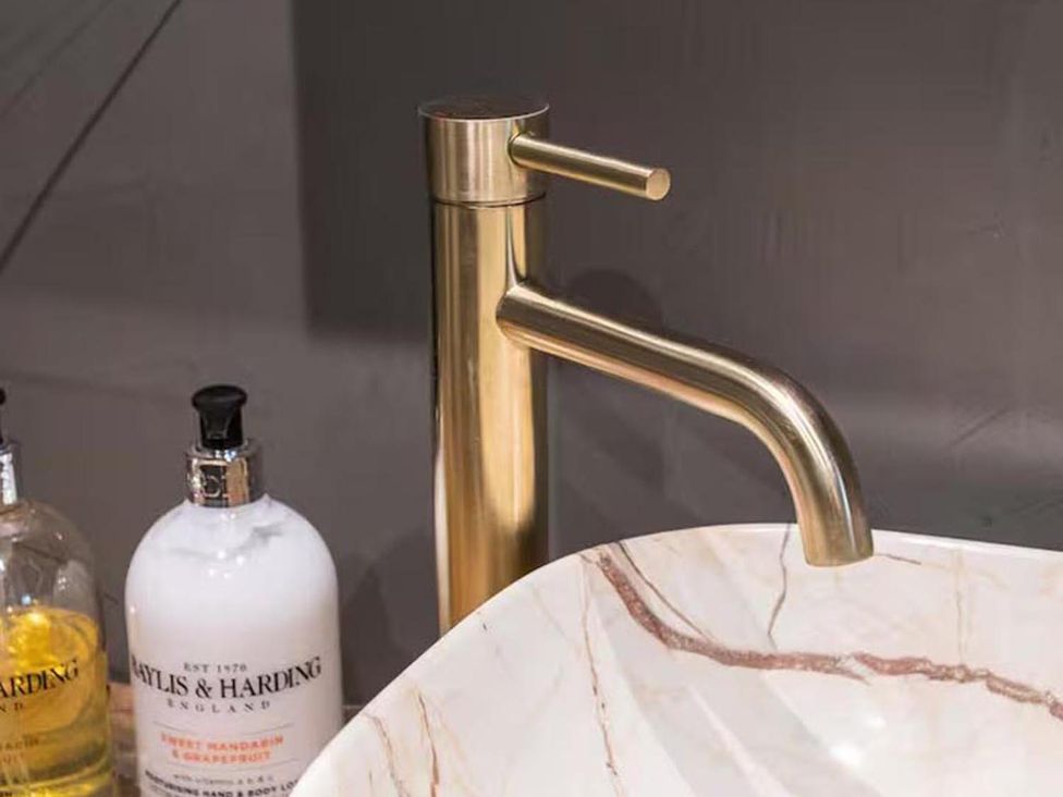 A faucet and soap dispensers on a marble sink in a bathroom