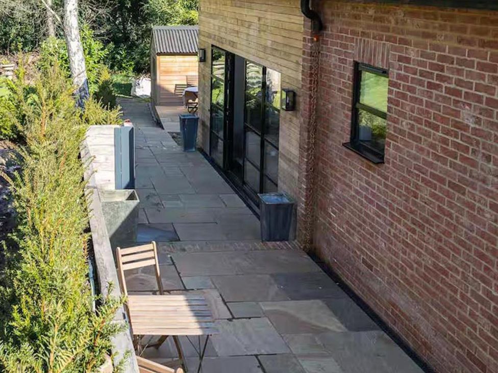 A patio area with a chair and bin at a property