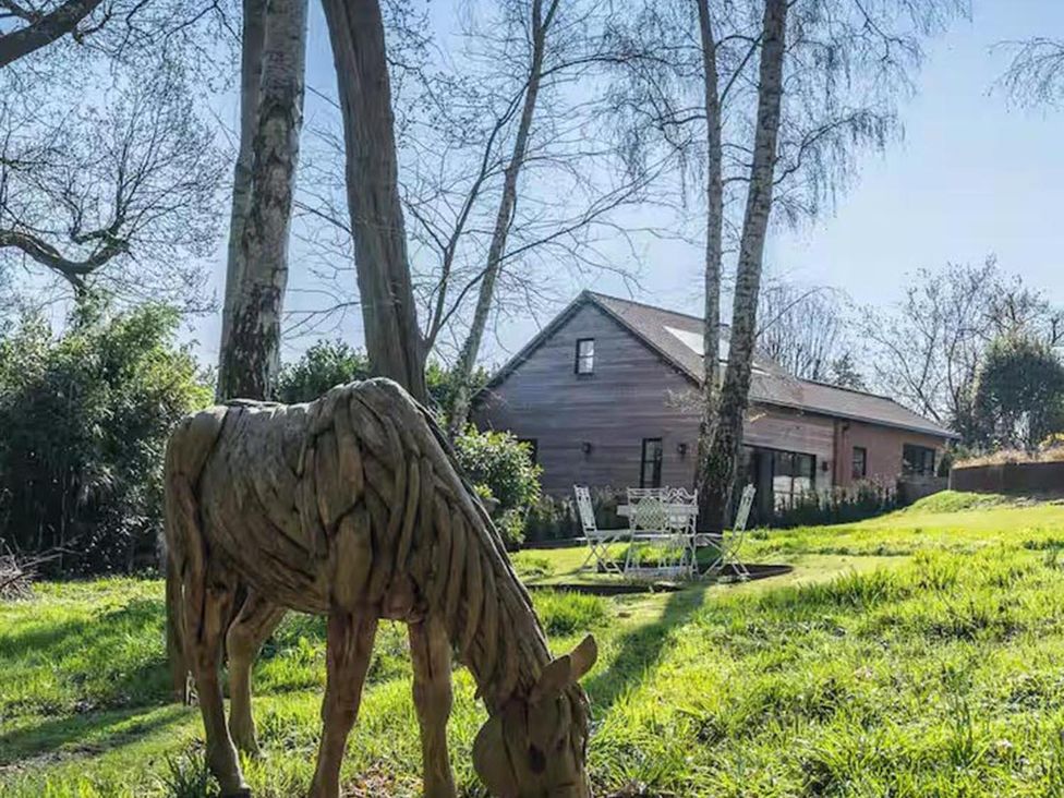 A garden with a horse sculpture and seating area at a property