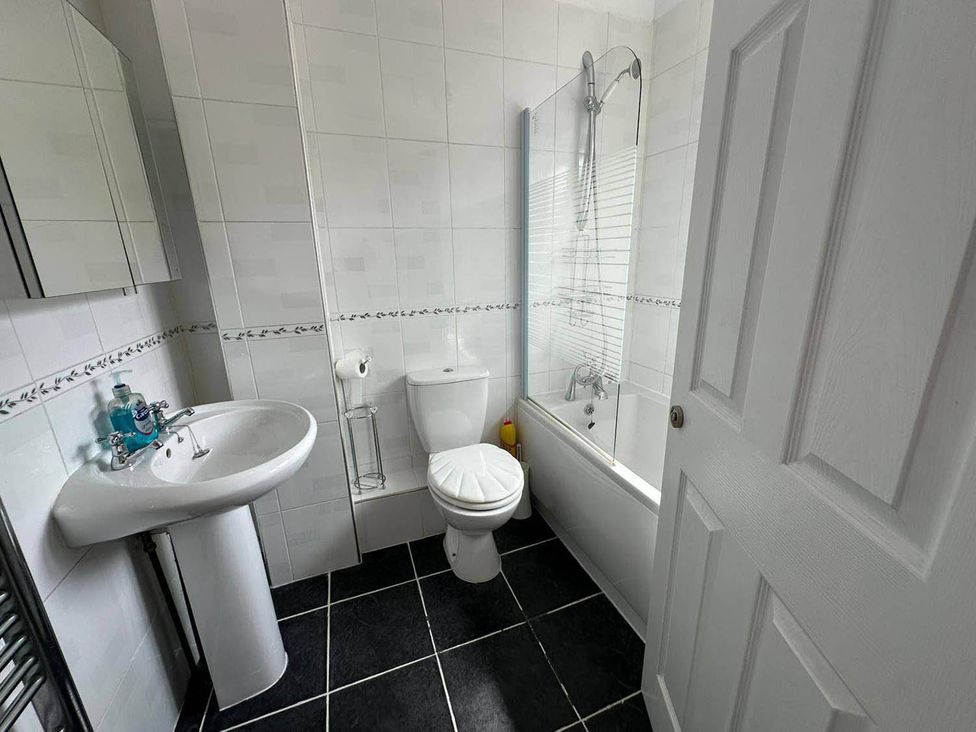 A bathroom with a bathtub, toilet, sink, and mirror at 4 Bed House Sleeps 8 Pets Parking Wifi