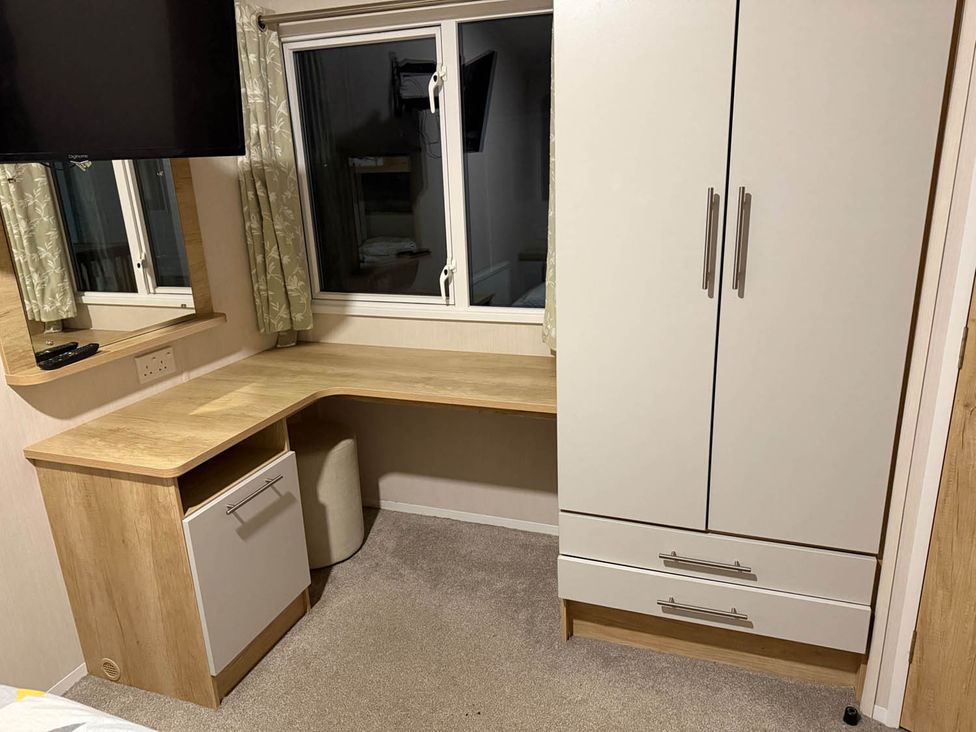 A bedroom with a desk, mirror, and cupboard at Charming Caravan in beautiful Seton Sands, Cockenzie And Port Seton
