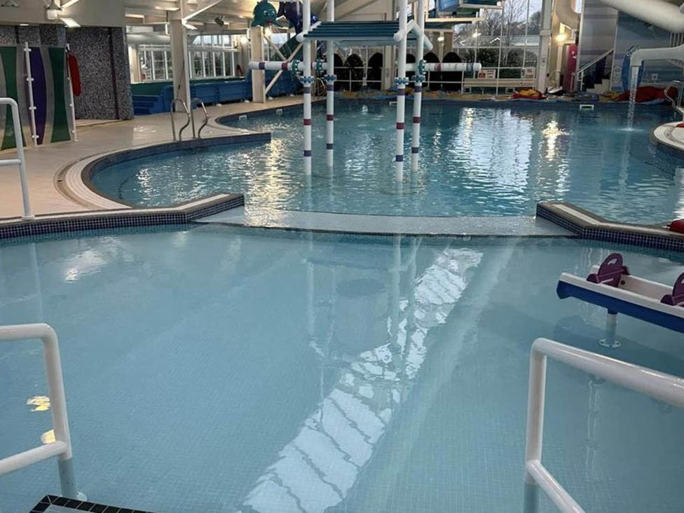 An indoor pool area with slides and lounge chairs at Charming Caravan in beautiful Seton Sands Cockenzie And Port Seton