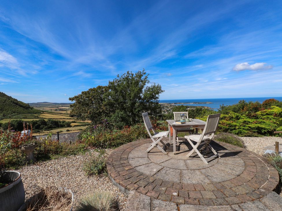 An outdoor seating area with a table and chairs overlooking the landscape at Hafod in Nefyn