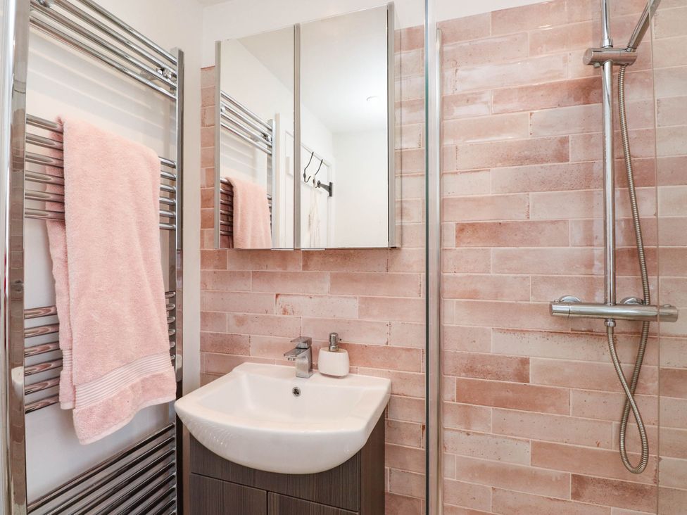 A bathroom featuring a sink, towel radiator, and shower at Hafod in Nefyn
