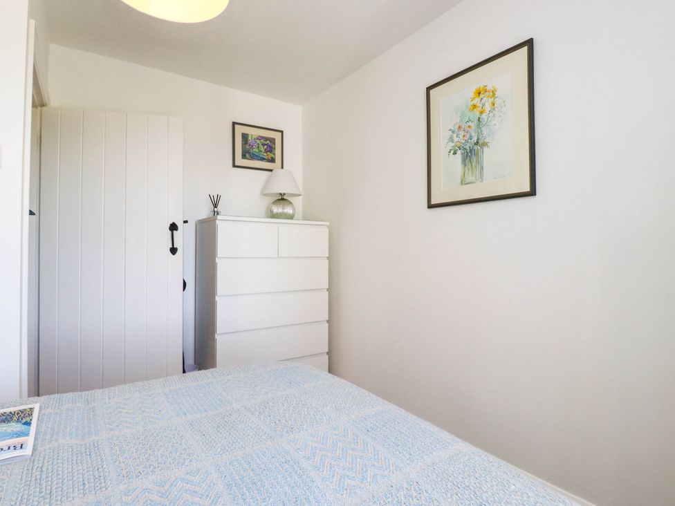 A bedroom with a bed and dresser at Hafod in Nefyn