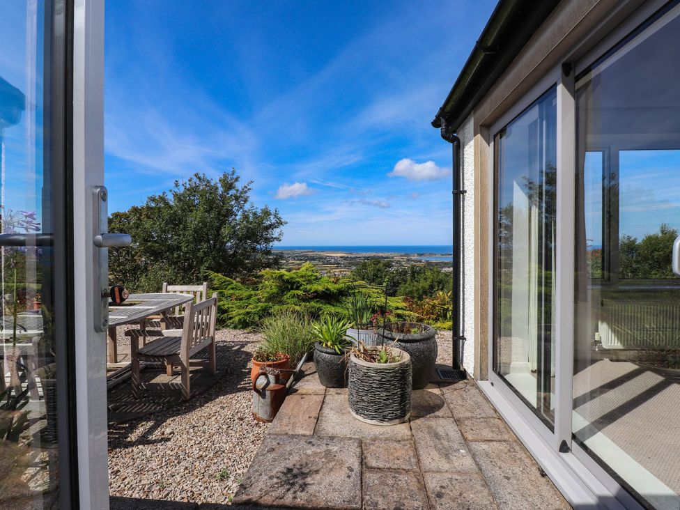 An outdoor patio with a table and chairs overlooking a coastal view at Hafod in Nefyn