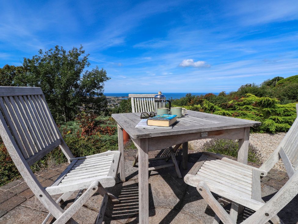 An outdoor dining setup with a table and chairs and a sea view at Hafod in Nefyn
