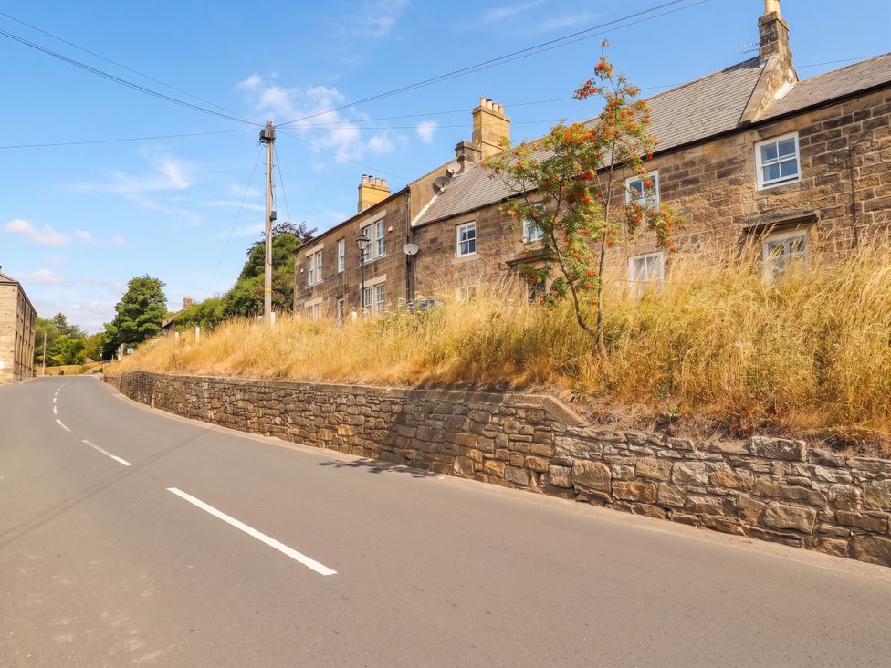 A street with houses and a stone wall at Cooper's Cottage in Morpeth