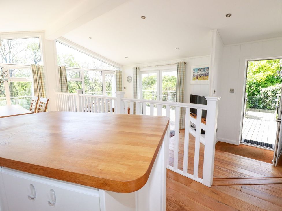 A kitchen with a wooden island and dining area at 4 Tree Tops in Liskeard