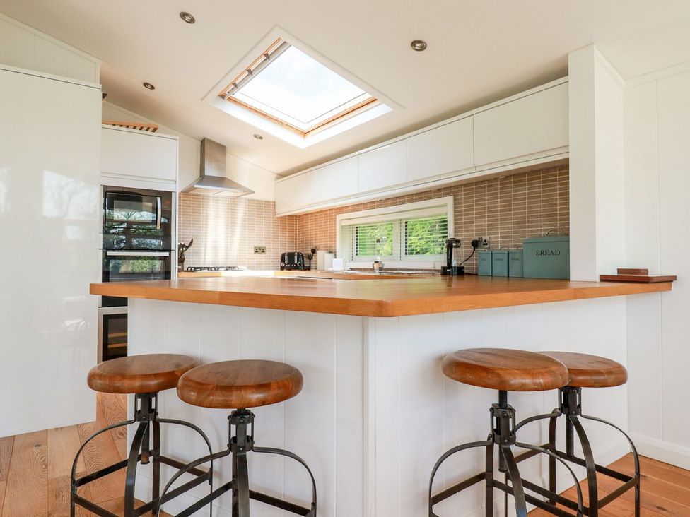 A kitchen with bar stools and appliances at 4 Tree Tops in Liskeard