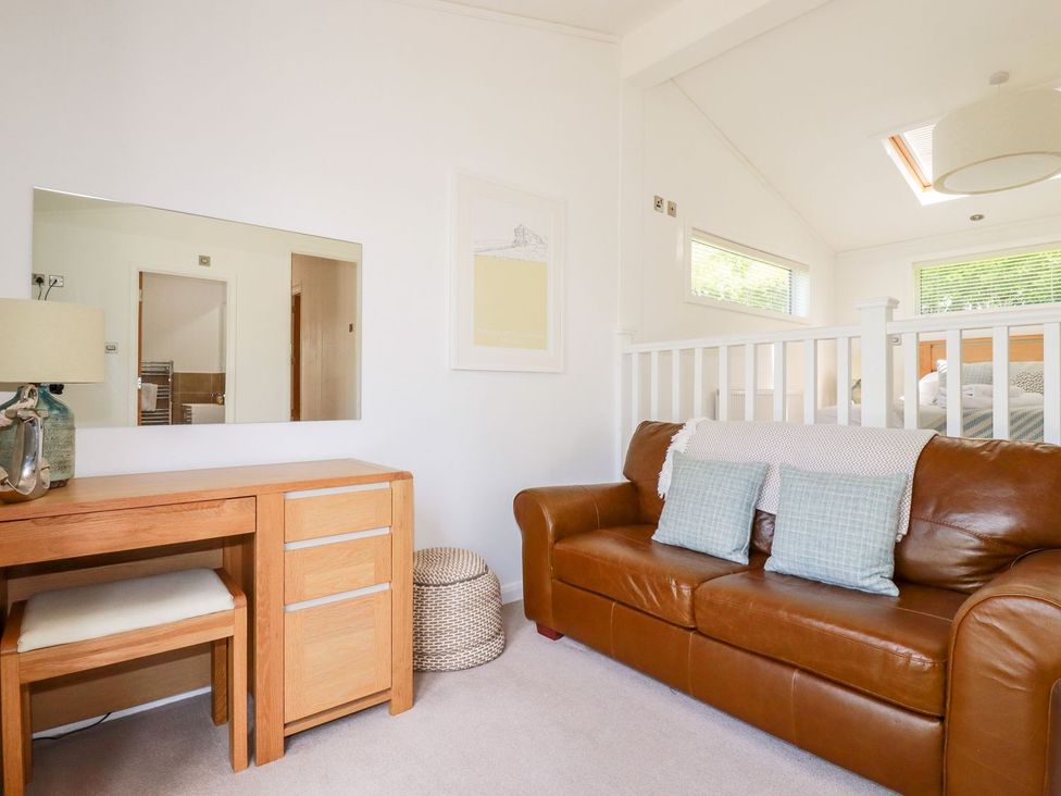 A living room with a sofa and desk at 4 Tree Tops in Liskeard