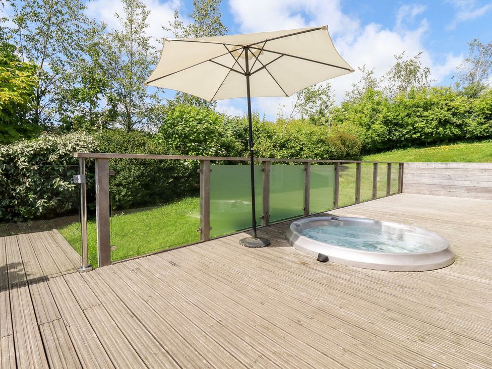 An outdoor area with a hot tub and a parasol at 4 Tree Tops in Liskeard