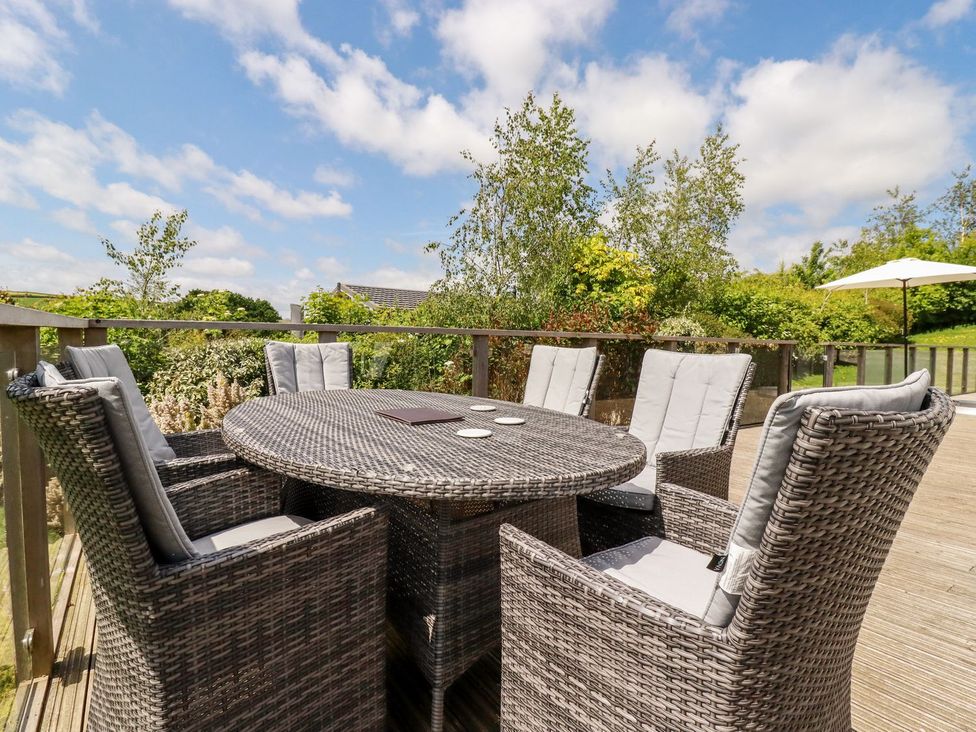 An outdoor seating area with a round table and chairs at 4 Tree Tops in Liskeard