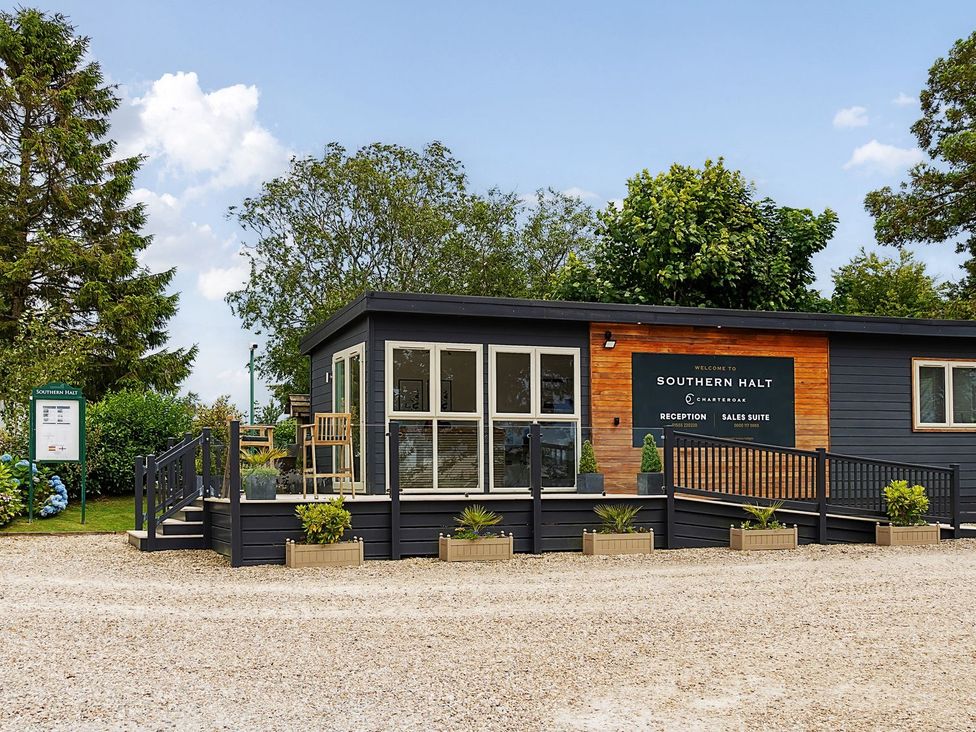 A reception building with sign and chairs at Southern Halt in Dobwalls
