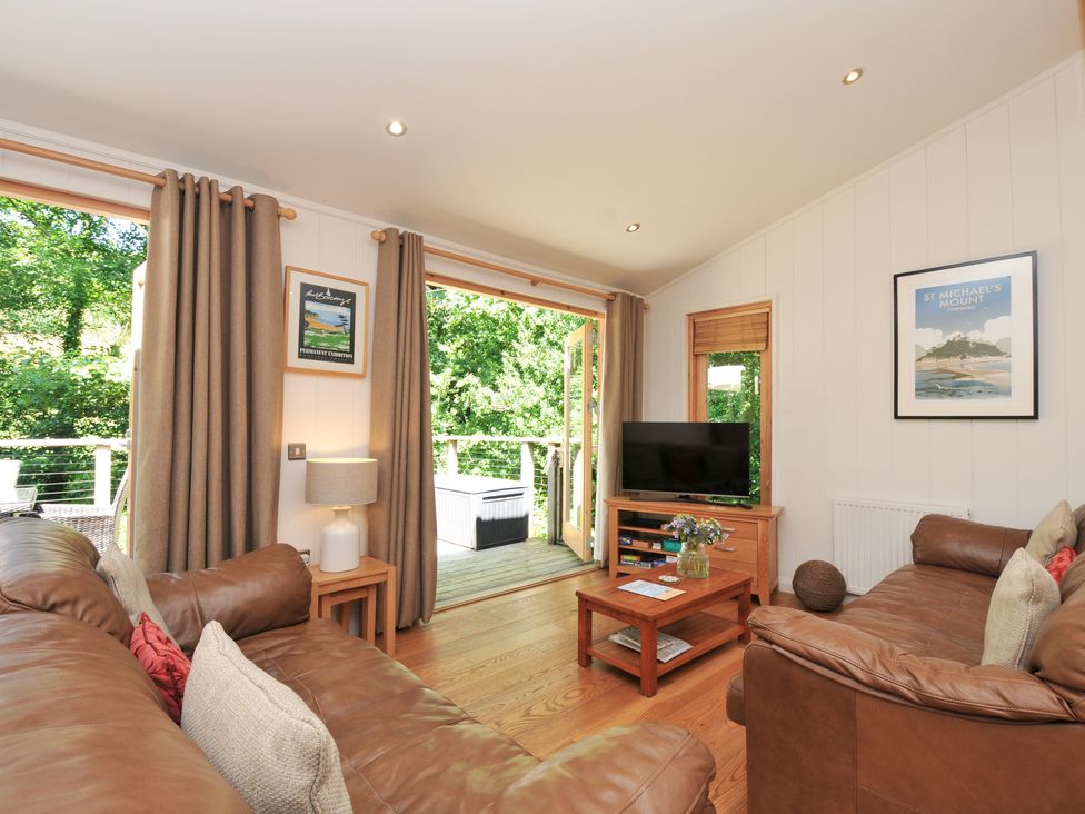 A living room with a sofa and a television at 1 Stonerush Valley in Liskeard